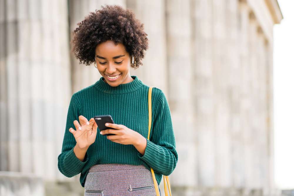 young african american woman performing a local seo search on her mobile phone and smiling, local search and consumer behavior