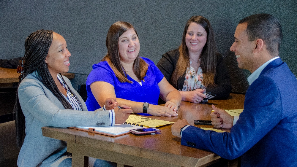 group of marketing professionals smiling and talking over a conference table