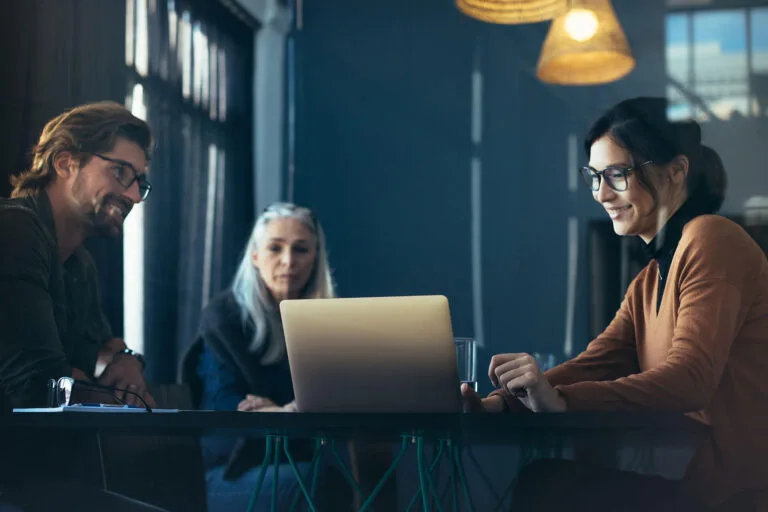 marketing professionals looking at a laptop screen on a table and smiling