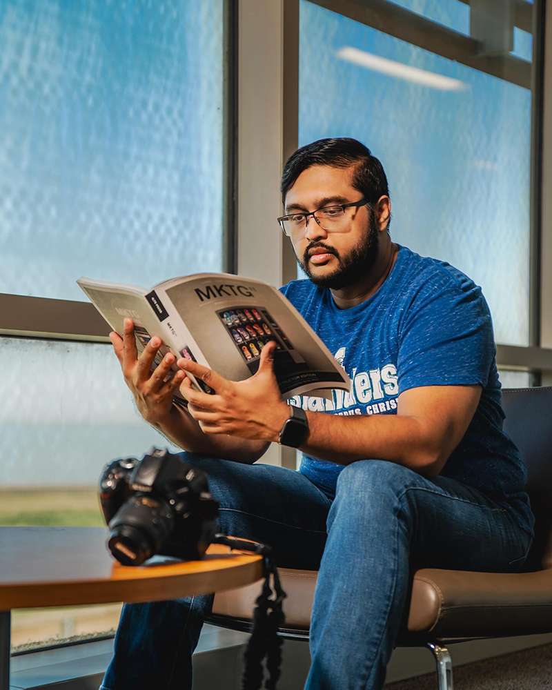 musanna al-muntasir sitting and reading a magazine at Texas A&M University's College of Business