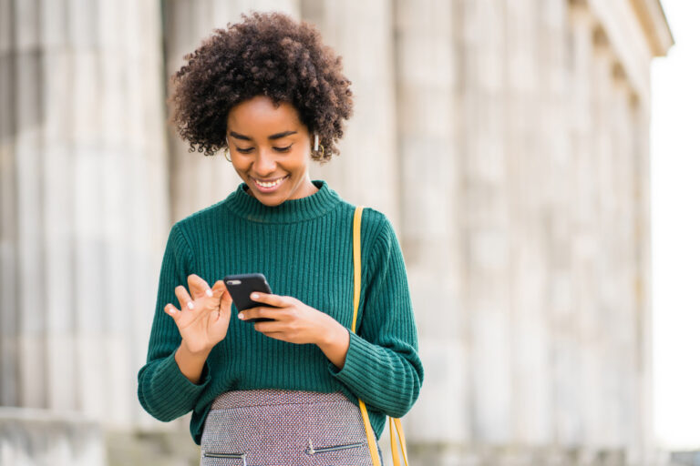 young african american woman performing a local seo search on her mobile phone and smiling, local search and consumer behavior